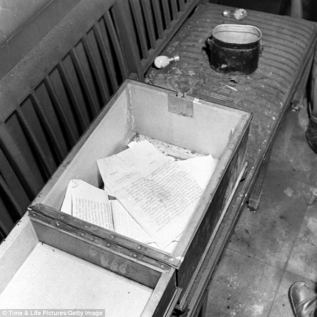 Ripped documents line the bottom of a large container near to a desk. The series of images were published in Life Magazine in July 1945