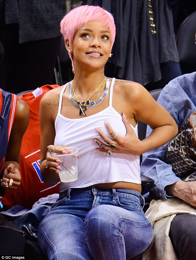 Raunchy: Rihanna playfully cuys her left breast while watching Los Angeles Clippers take on Oklahoma City Thunder at the Staples Center in Los Angeles on Thursday