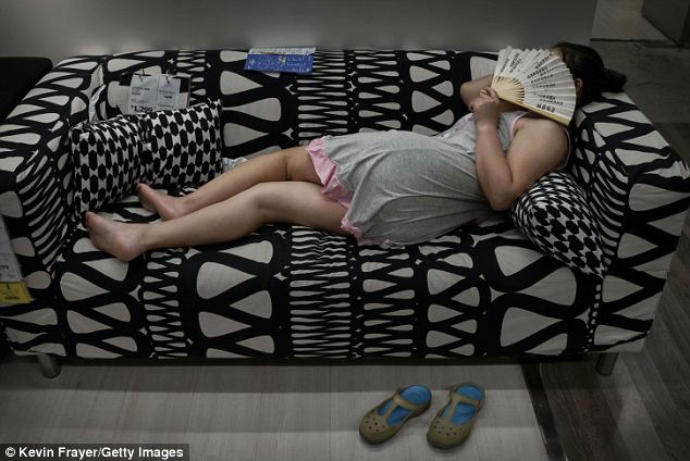 No pictures! A woman hides her face with a fan after kicking off her shoes and putting her feet up on a sofa