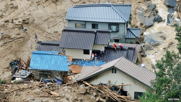 Local residents wait for rescuers on collapsed houses after a massive landslide swept through a residential area in Hiroshima, western Japan, on 20 August 2014
