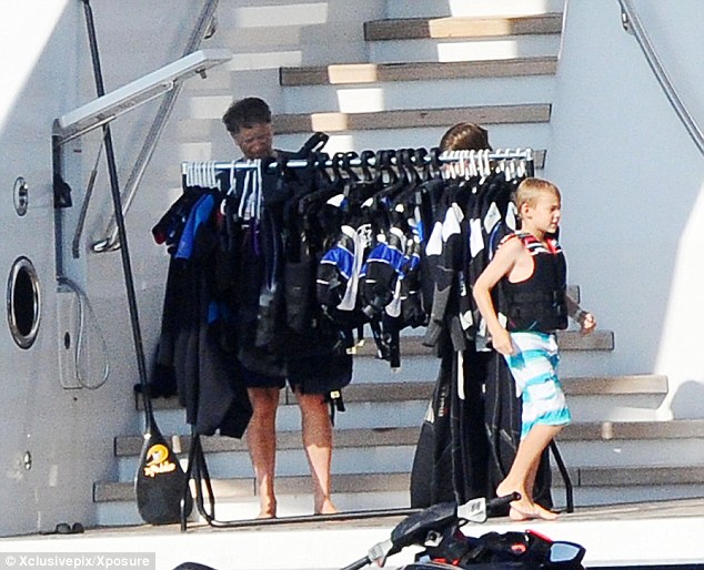Which wetsuit? Bill Gates looks for suitable gear to wear for a jetski while his son, Rory, runs past him