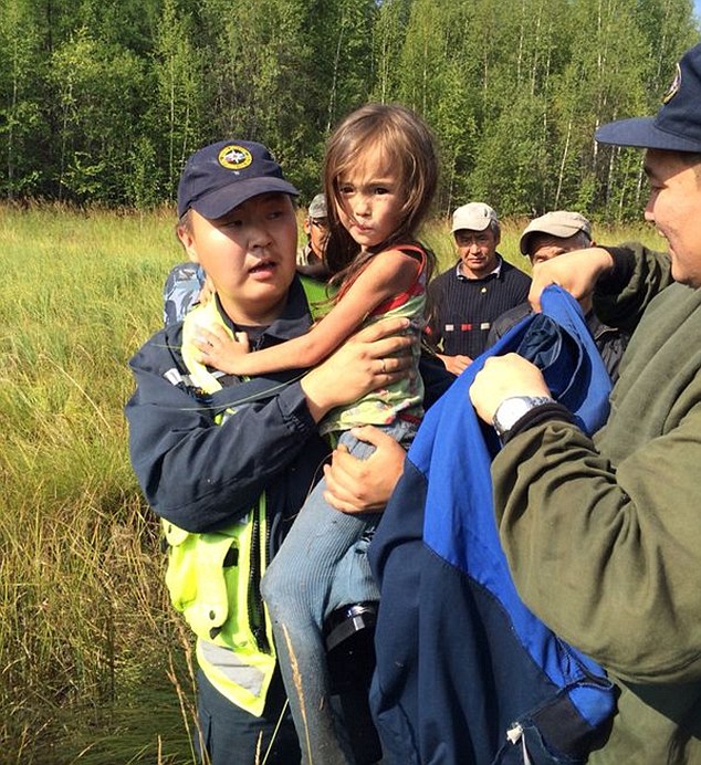 Lucky: Rescuers hold little Karina Chikitova who survived eating wild berries and drinking river water