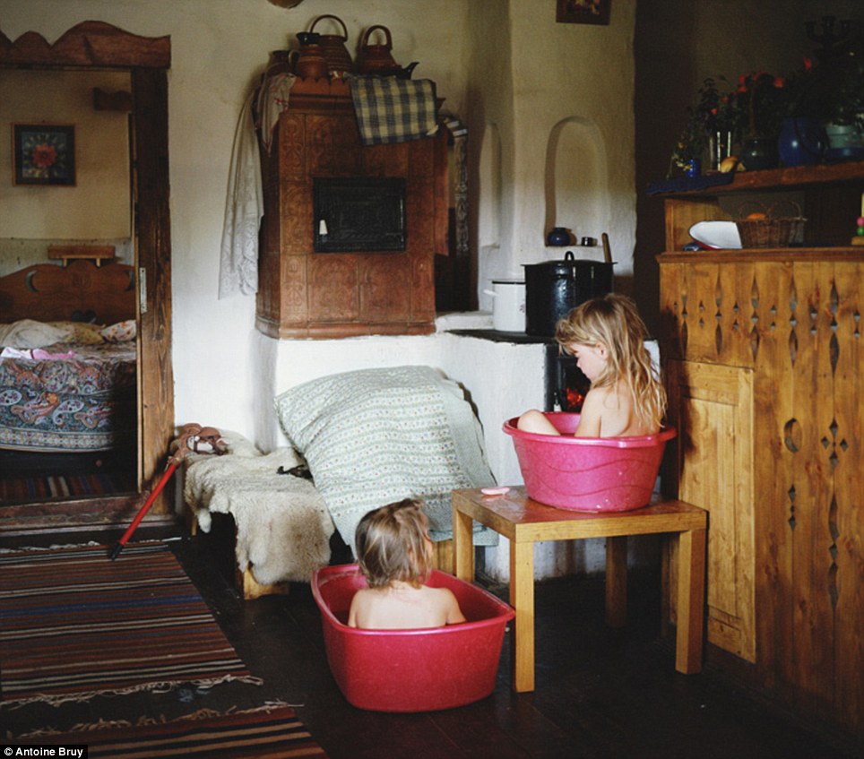 Humble existence: The French photographer has documented families who have chosen to turn their backs on the breakneck speed of modern life to become at one with nature. With no access to running water, these two girls take a bath in washing up tubs in the Carpathian mountains in Romania