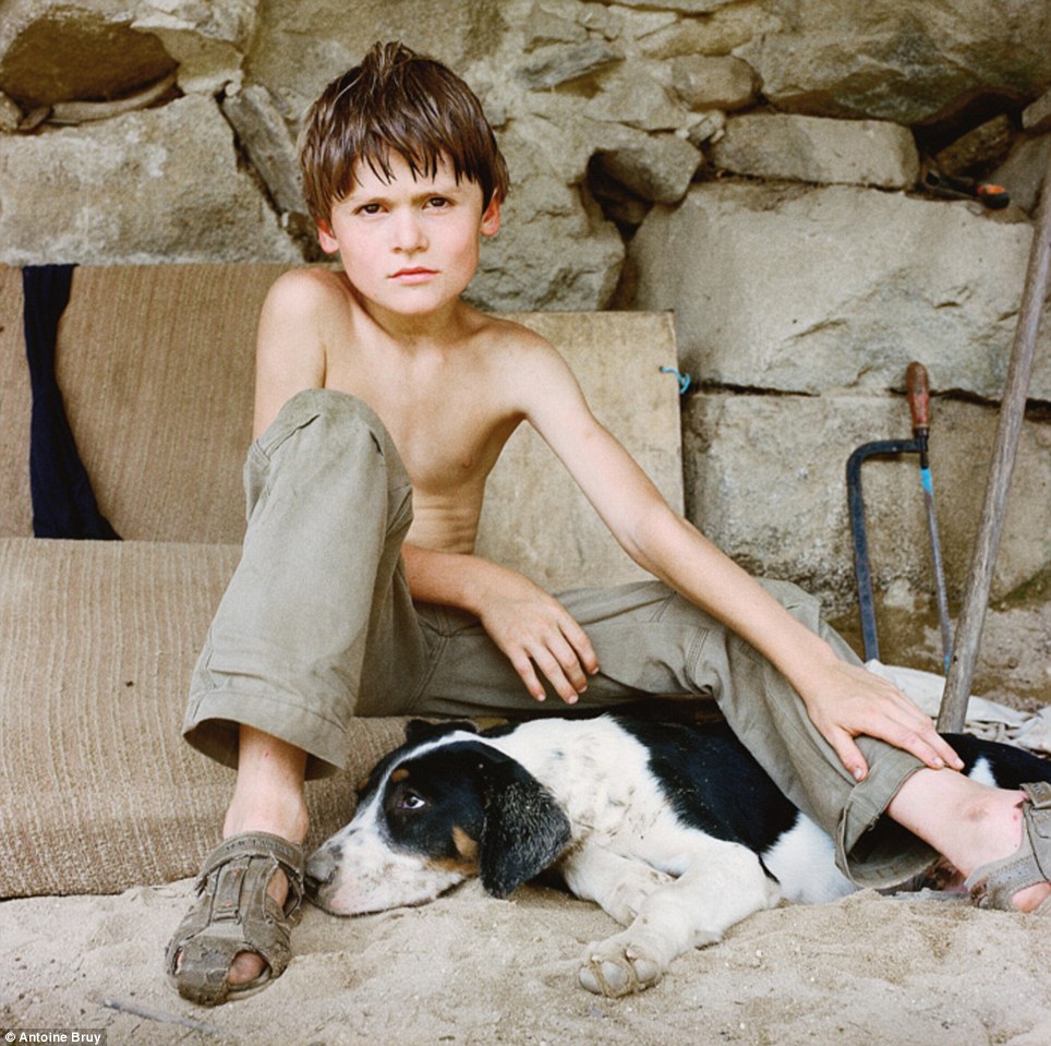 Life out of the fast lane: A boy who has grown up in the so-called 'back-to-land' movement poses with his dog in Urs in The Pyrenees