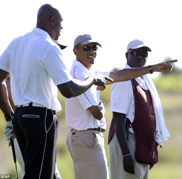 President Barack Obama speaks with former NBA basketball player Alonzo Mourning, left, while golfing at Vineyard Golf Club, in Edgartown on the island of Martha's Vineyard