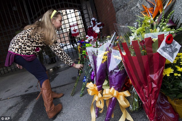 Chloe Hogan, of Hamilton, places flowers at a memorial outside the gates of the John Weir Foote Armory, the home of the Argyll and Sutherland Highlanders of Canada, with whom slain soldier Corporal Nathan Cirillo served before he was gunned down Wednesday