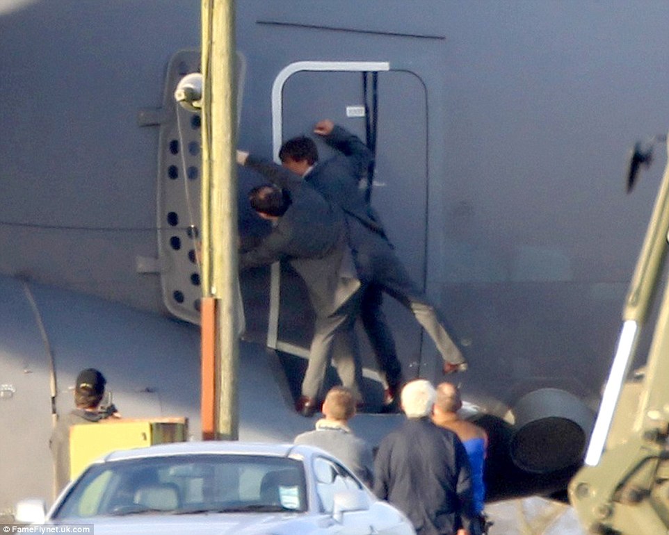 Acting it out: A double wears an identical suit to Cruise as the actor is guided into a horizontal position for flight on set