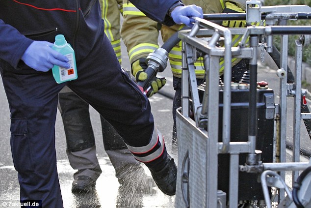 A firefighter disinfects and hoses down the protective clothing worn to rescue the morbidly obese man 