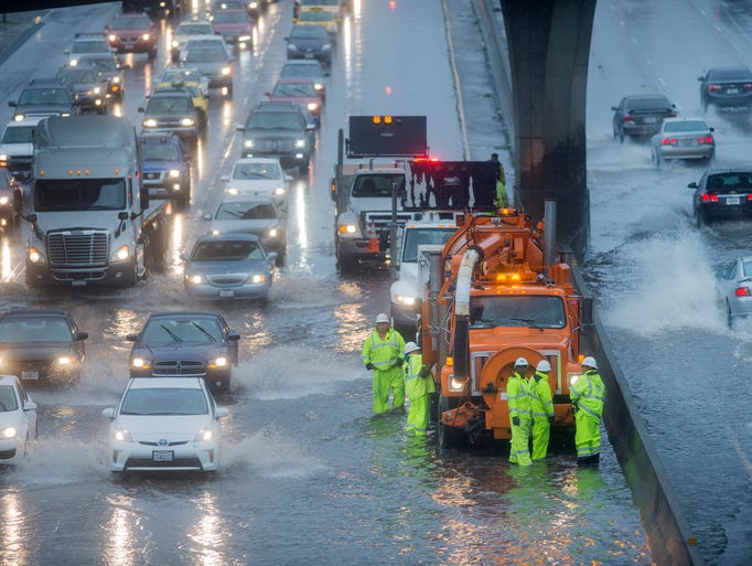 A Caltrans crew tries to clear a flooded stretch of