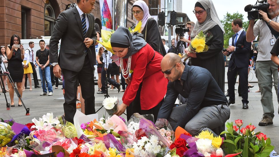 Representatives of the Muslim community lay flowers at a floral memorial at the scene of a dramatic siege which left two hostages dead in Sydney