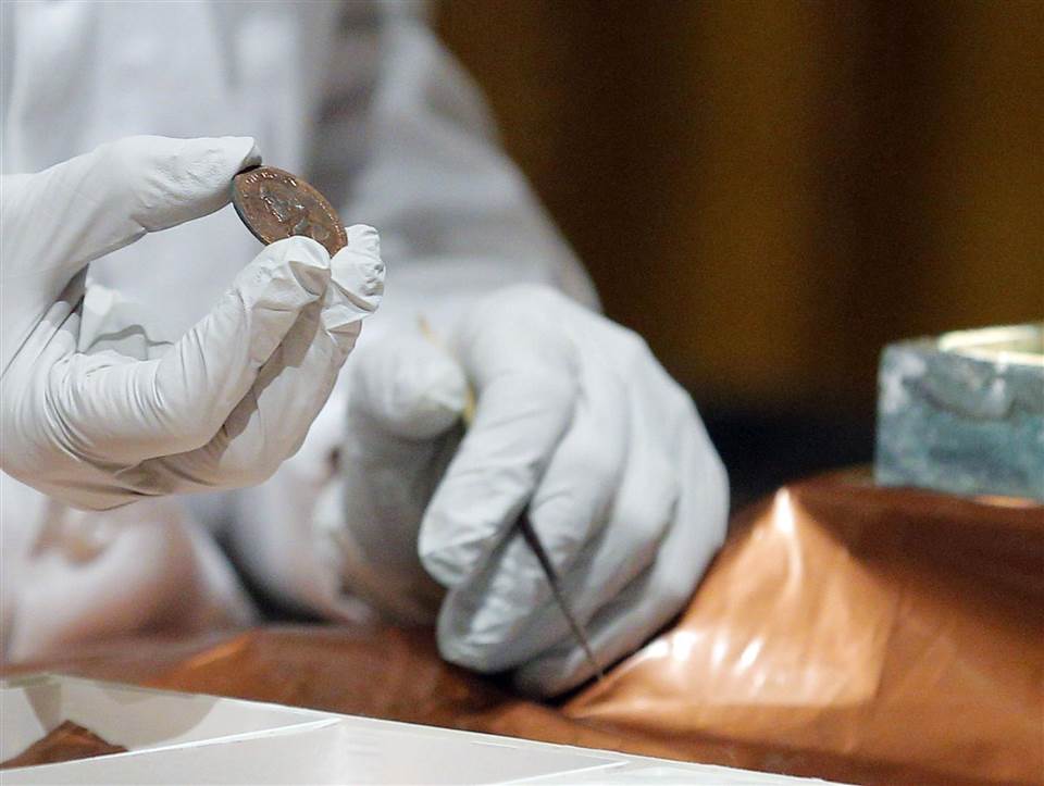 Image: Conservator Hatchfield holds a copper medal
