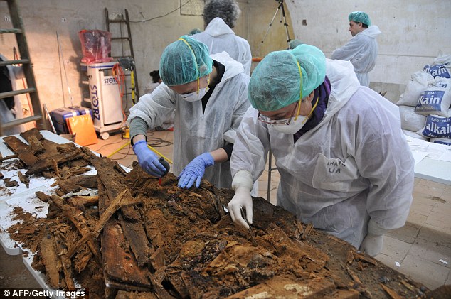 Experts pic through the broken coffins and dirt looking for bone fragments and other evidence