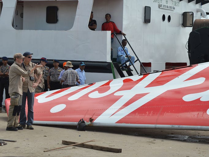 Foreign investigators, left, examine the tail of the