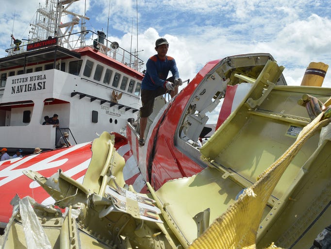 An Indonesian worker cuts metal on the recovered tail