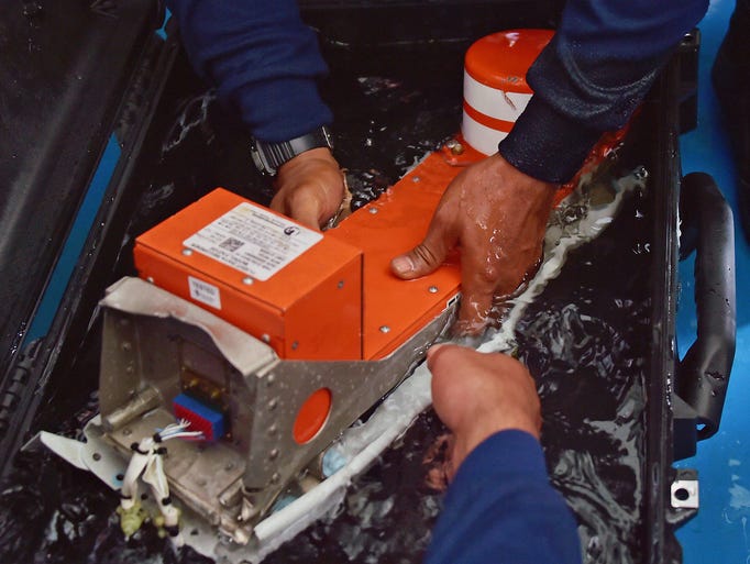 Navy divers place the flight data recorder into a protective