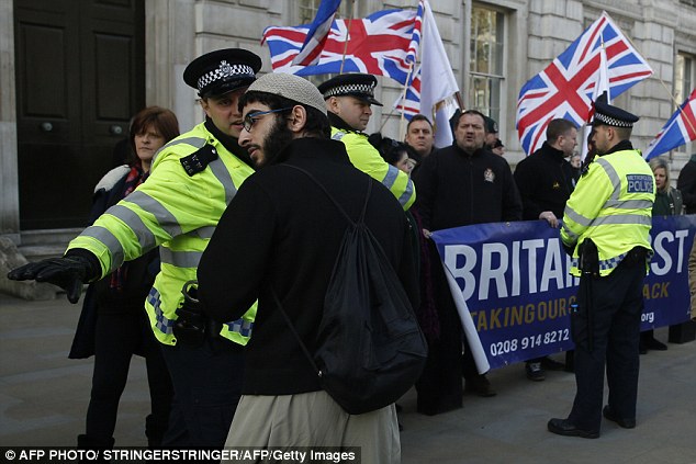 Stand-off: A Muslim protester is directed away from a nationalist counter-demonstration by far-right group Britain First