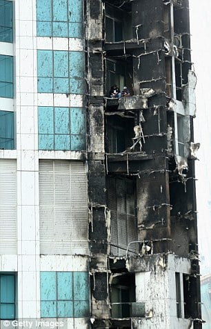 Aftermath: Two men inspect the damage on the decimated balcony of one of the apartments in the Torch