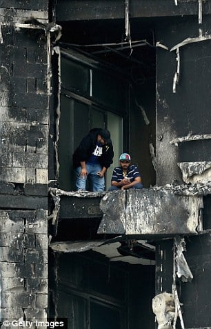 Aftermath: Two men inspect the damage on the decimated balcony of one of the apartments in the Torch
