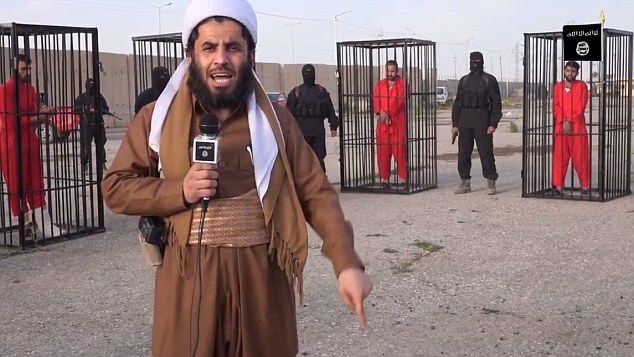 A militant, whose microphone bears insignia associated with the terror group, talks to the camera in front of the cages