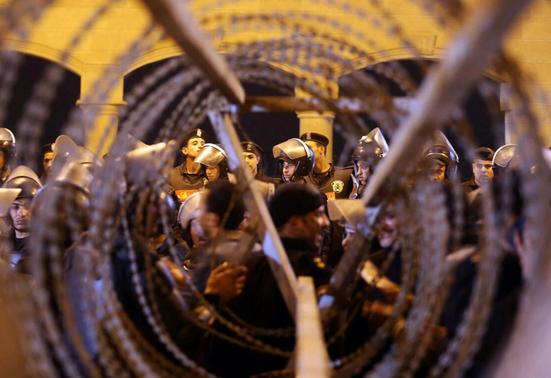 Policemen and soccer fans are seen through barbed wire as fans attempt to enter a stadium to watch a match, on the outskirts of Cairo February 8, 2015.  REUTERS-Al Youm Al Saabi Newspaper
