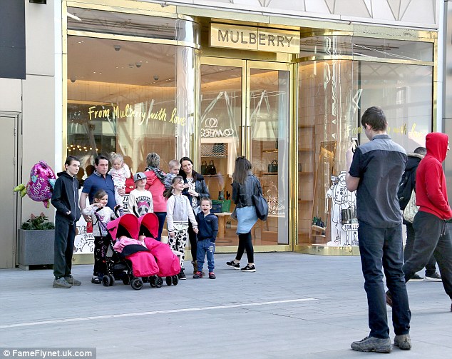 The family pose for a picture outside the store. Mrs Prudham is a pregnant mother of 11 and receives £39,000 a year in benefits 