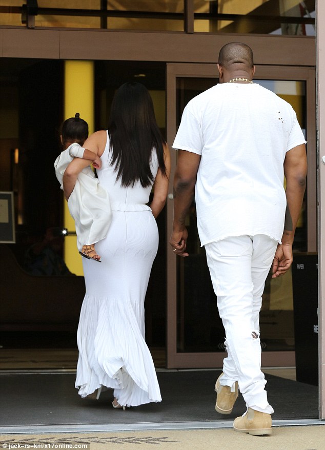 Off they go: Kim continued to hold her little girl as they headed inside the church 