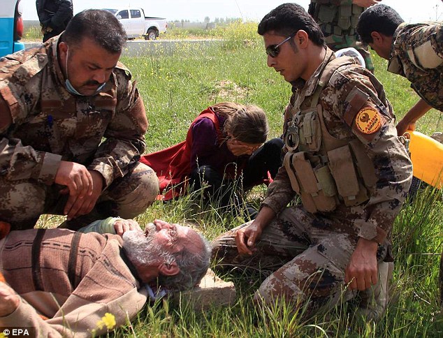 Released: An elderly Yazidi man is being cared for by peshmerga troops while a young girl cries as she is being offered water by a Kuridsh soldier after their release near Kirkuk, northern Iraq