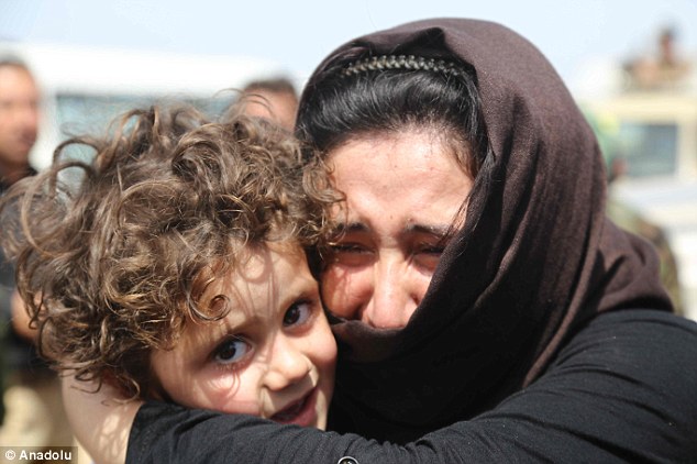 Free at last: A mother hugs here young child in celebration at being released. The freed Yazidis were taken away by ambulances and buses to receive treatment and care