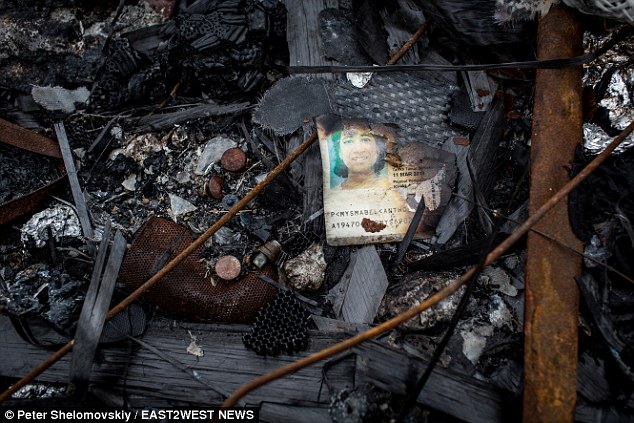 Chilling: MailOnline's photographer spotted the burned and torn passport of loving wife and mother Mabel Anthonysamy Soosai, 45, one of the 298 slaughtered when MH17 was downed over Ukraine on July 17, 2014. Her family in Kuala Lumpur has given MailOnline permission to publish the picture