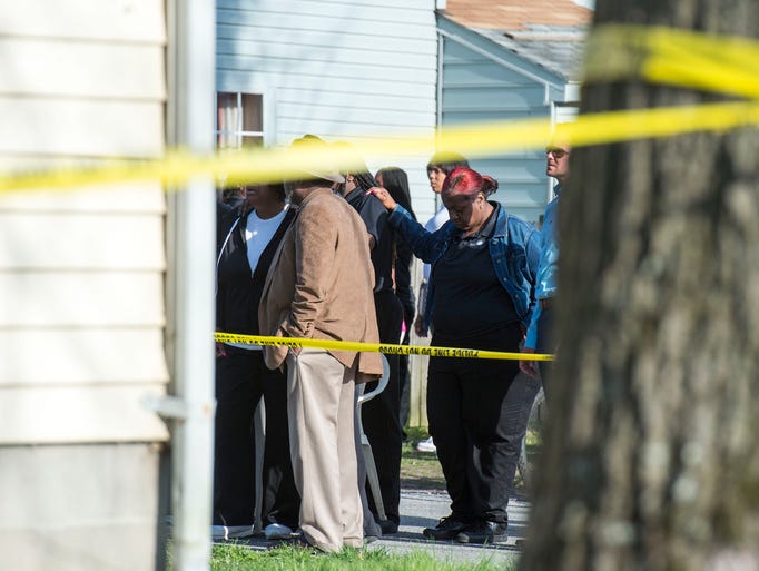Onlookers gather outside of an Antioch Ave house, where