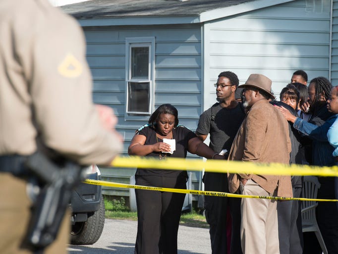 Onlookers gather outside of an Antioch Avenue house