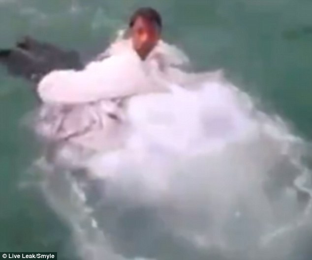 The woman's groom (pictured) frantically tried to lift her head above the water but the dress was too heavy