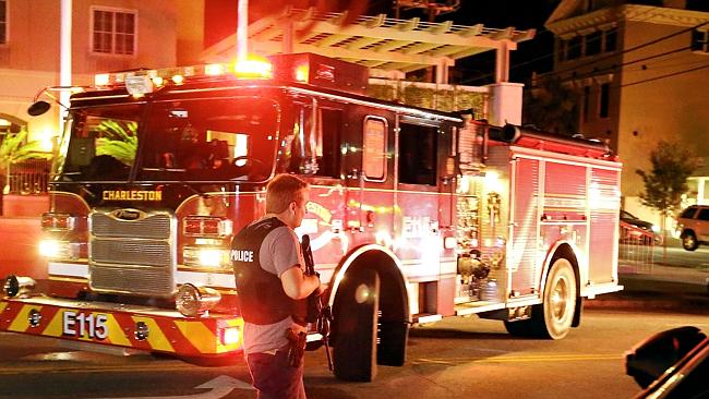 An armed police officer moves up Calhoun Street following a shooting in Charleston. Pictu