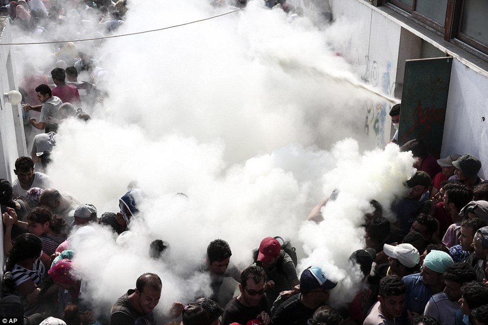 Covered: A handful of police officers resorted to blasting the crowds with foam, causing hundreds of migrants to flee in panic