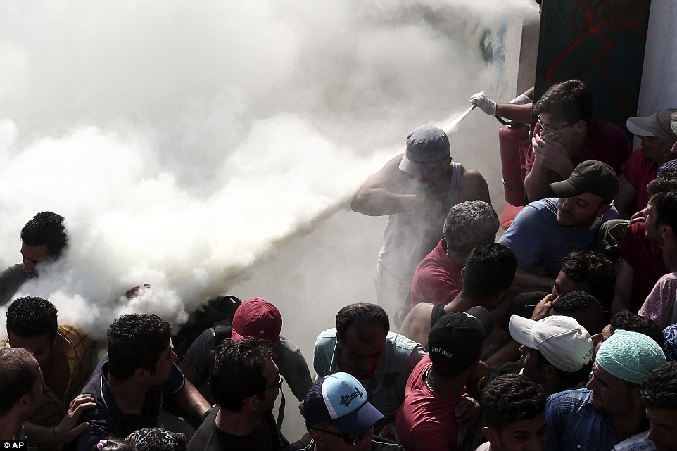 Policemen try to disperse hundreds of migrants by spraying them with fire extinguishers, on the Greek island of Kos this morning