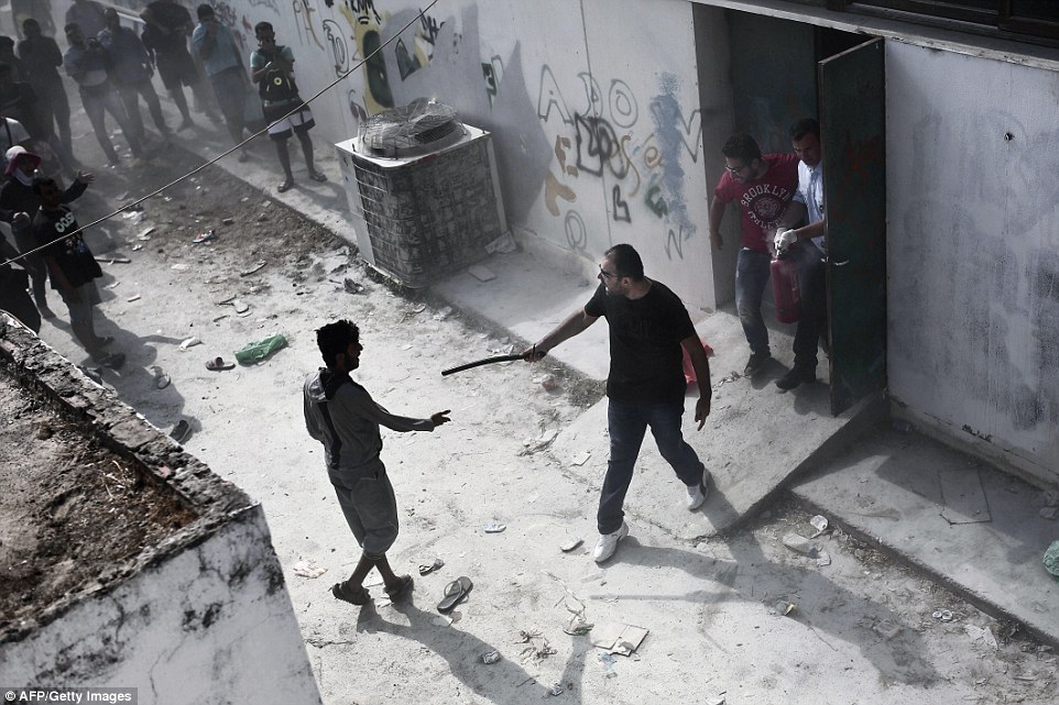 A policeman confronts a migrant with a truncheon during a registration procedure at the stadium on the Greek island of Kos today