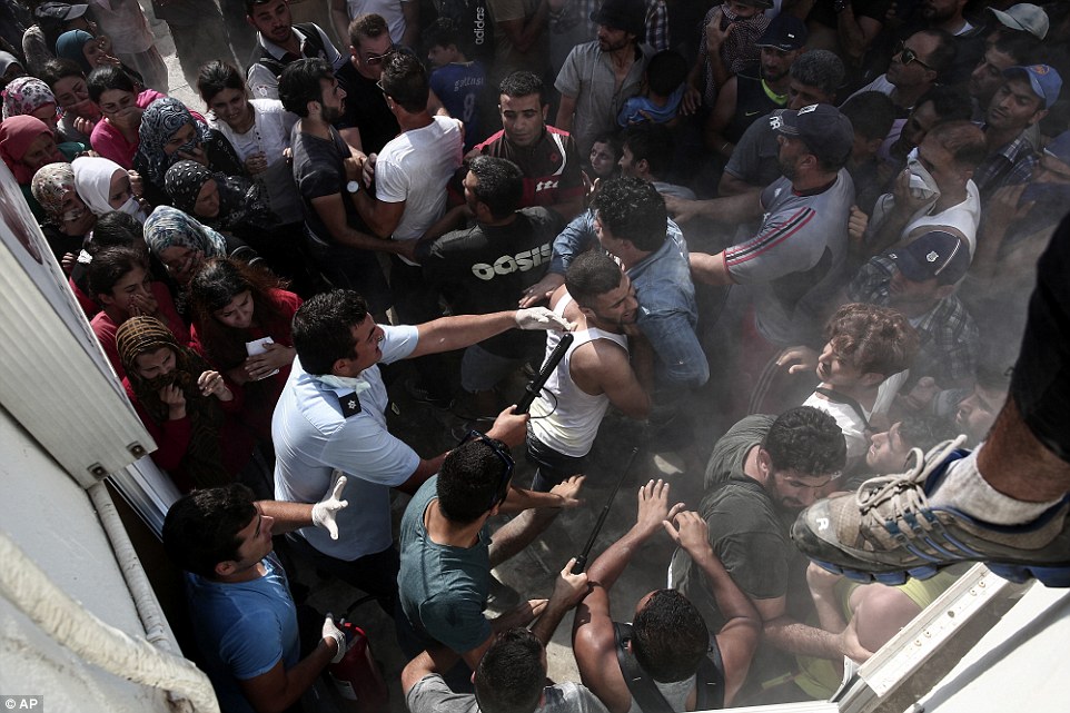 Pushing: A policeman hits a migrant as police try to disperse hundreds of migrants during a registration procedure in Kos town today