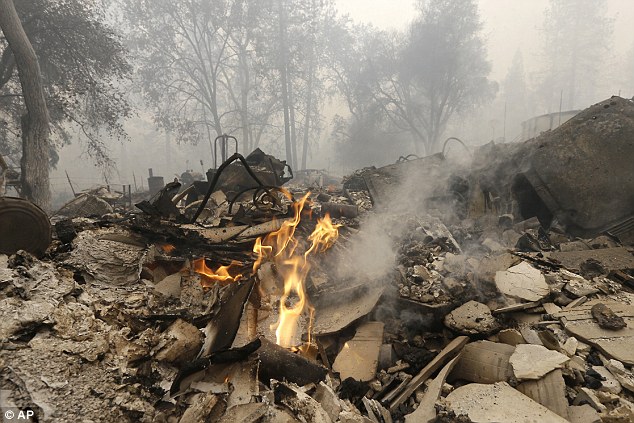 Flames burn in the remains of a home destroyed by the Butte Fire, Saturday, Sept. 12, 2015, in Mountain Ranch