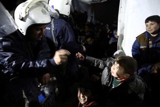 Αστυνομικός των ΜΑΤ προσφέρει μία καραμέλα σε πρόσφυγα στην Ειδομένη