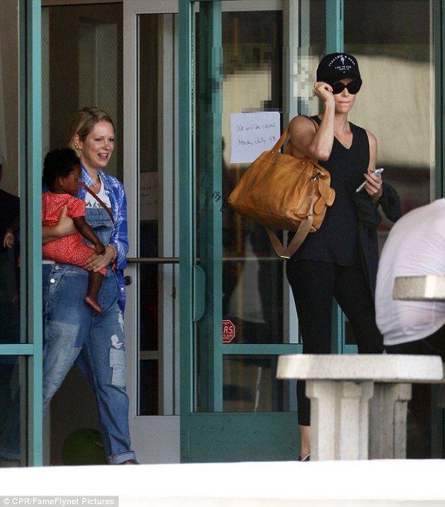 Helping hand: Charlize was seen leaving the children's gym with cell phone and diaper bag while a helpful pal carried August