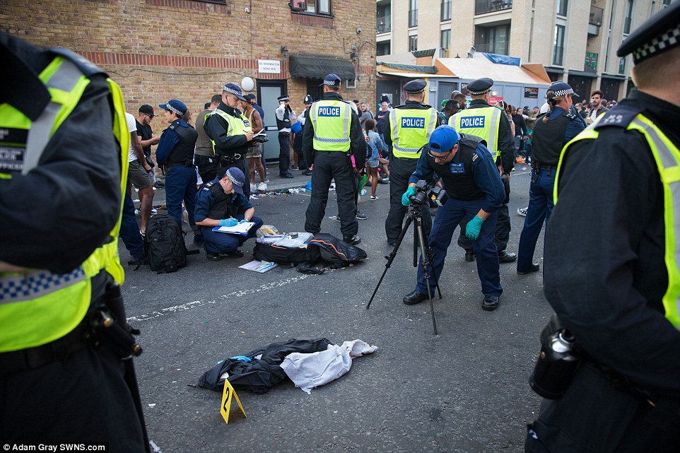 Gathering evidence: Six people have been stabbed in a series of knife attacks which have overshadowed the first day of the Notting Hill Carnival celebrations in London. Police are pictured at the scene of one of the incidents on Sunday