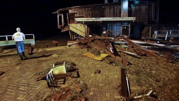 A member of Cedar Key Fire Rescue checks on damage from Hurricane Hermine to a building on the waterfront early Friday, 2 September 2016, in Cedar Key, Fla.