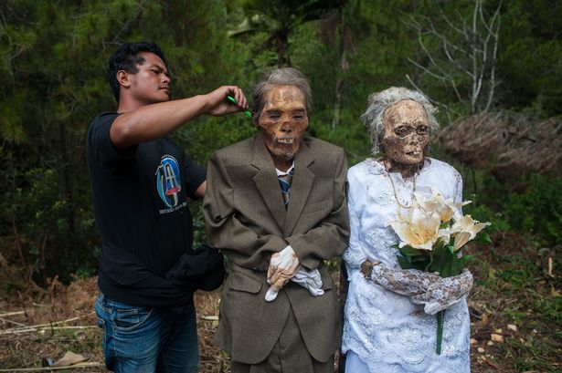 Herman Tandi (32) combs the hair of his grandparents Jesaya Tandibua' (left) and Yakolina Namanda during the Ma'nene ritual at Panggala Village on August 26, 2016 in Toraja, Indonesia.