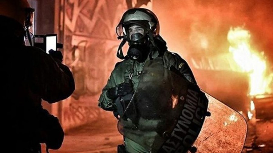 Η στιγμή που άνδρας των ΜΑΤ ποζάρει μπροστά στους φλεγόμενους κάδους – ΦΩΤΟ