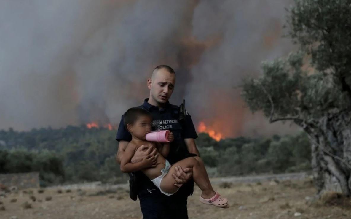 Αστυνομικός μεταφέρει παιδάκι στην αγκαλιά τους για να το σώσει από τη φωτιά