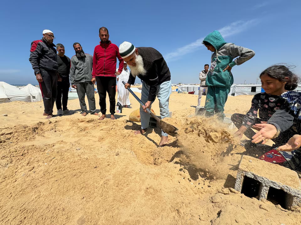People bury the body of displaced Christian Palestinian Hany Dawood, who died of a kidney disease, at a Muslim graveyard, as his family was not able to receive his body and bury him at the Christian cemetery in Gaza City due to Israeli measures that ban the movement from the south of the Gaza