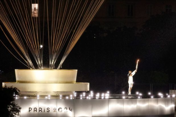 Οι λαμπαδηδρόμοι Marie-Jose Perec και Teddy Riner φτάνουν για να μεταφέρουν την ολυμπιακή φλόγα στο αερόστατο κατά την διάρκεια της τελετής έναρξης των Ολυμπιακών Αγώνων 2024, στο Παρίσι, 26 Ιουλίου 2024.