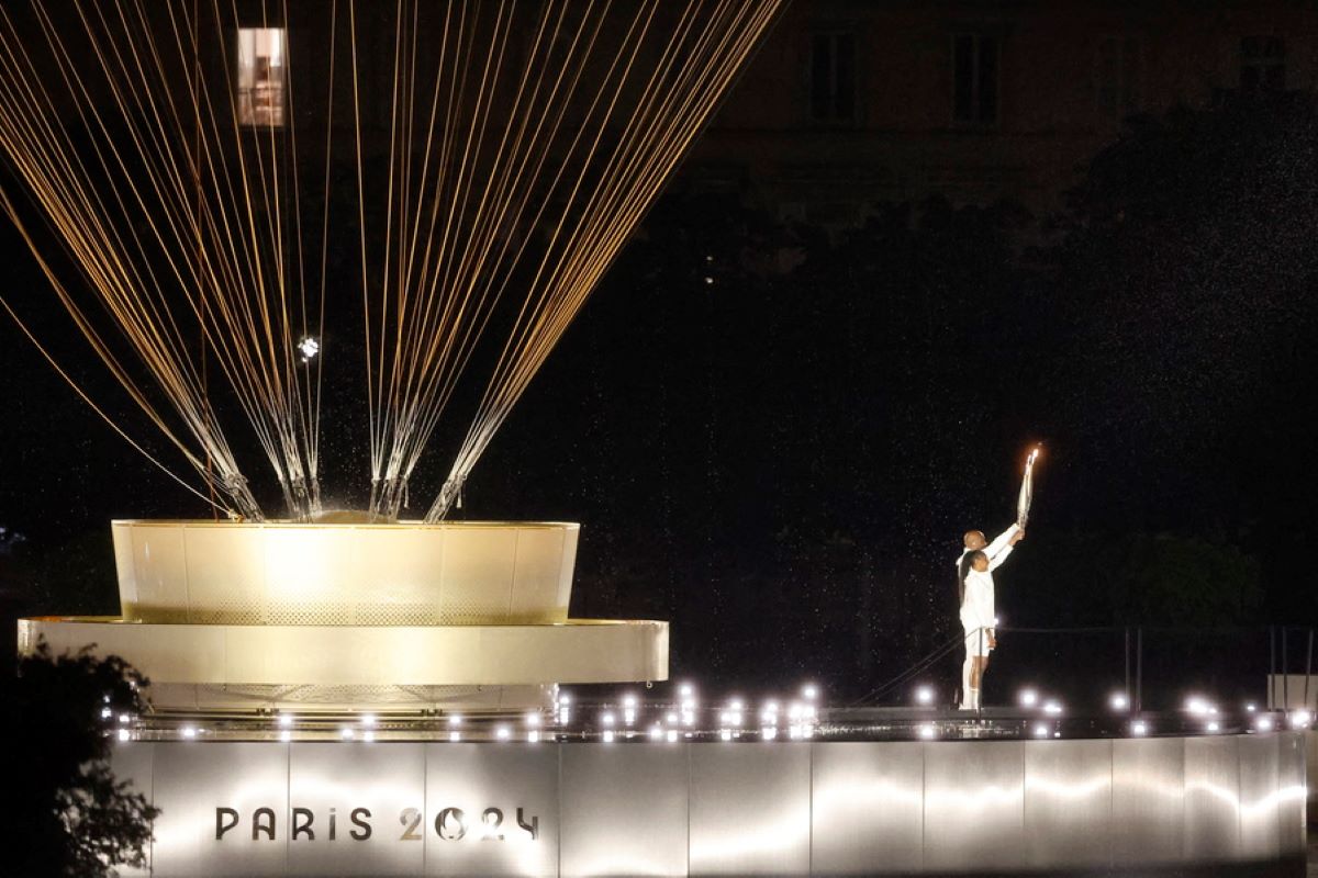 Οι λαμπαδηδρόμοι Marie-Jose Perec και Teddy Riner φτάνουν για να μεταφέρουν την ολυμπιακή φλόγα στο αερόστατο κατά την διάρκεια της τελετής έναρξης των Ολυμπιακών Αγώνων 2024, στο Παρίσι, 26 Ιουλίου 2024.