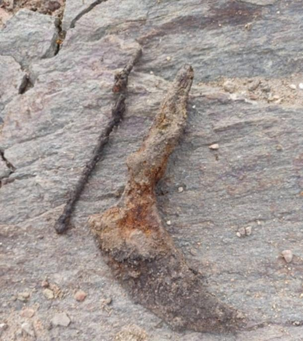 Το μαχαίρι με την καμπυλωτή άκρη, που χρησιμοποιείται κανονικά για την επεξεργασία δέρματος, και μια βελόνα για ράψιμο. Αυτά τα αντικείμενα είναι πιο κοινά στους τάφους των γυναικών και συνήθως χρονολογούνται σε αιώνες γύρω στο έτος 0. Φωτογραφία: Karin Lindeblad/Arkeologerna