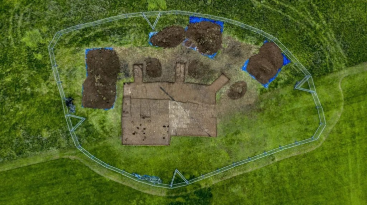 Εναέρια λήψη του σημείου των ανασκαφών. Η κύρια περιοχή έχει ανασκαφεί σε ένα αδρό τετράγωνο σχήμα, με μια σειρά από μικρότερες, στρογγυλές τάφρους γύρω της. Φωτογραφία: Vivian Thomas